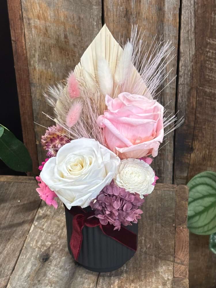 Preserved soft pink and white roses set in a black ceramic base with a mix of lovely preserved flowers